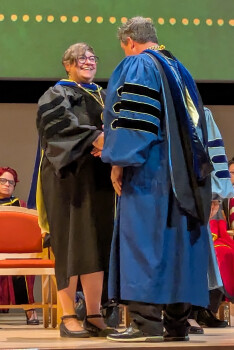 Dr. Seaman in regalia accepting a medal during the 2025 Investiture Ceremony at the UT Dallas ATC Lecture Hall.