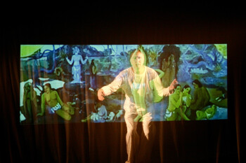 Fred Curchack as Paul Gauguin painting his masterpiece. A man seen through a projection of Gauguin's painting.