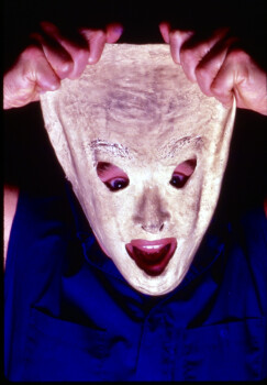 Man pulling a stretched, latex mask off of his face